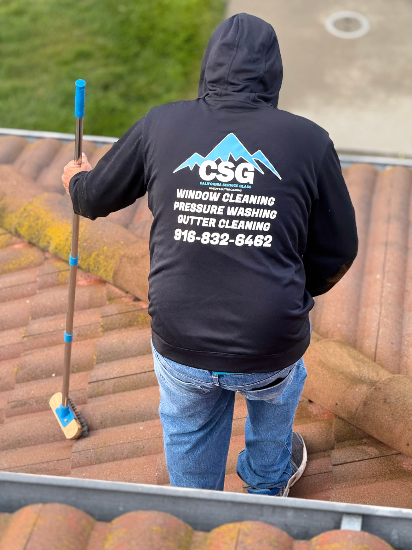 CSG technician removing moss from a red tile roof in the greater Sacramento area