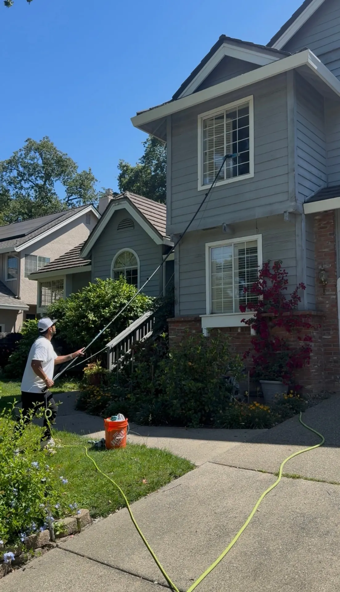 CSG technician cleaning second-story windows on a two-story home with a water-fed pole