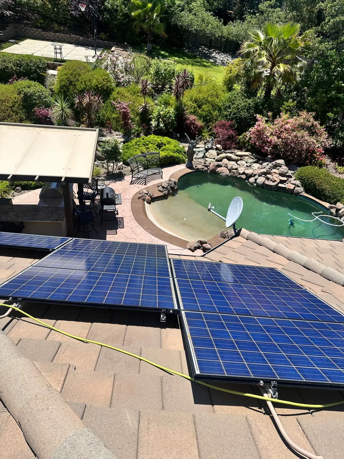 Rooftop solar panels cleaned by CSG on a tile roof in El Dorado Hills overlooking a landscaped backyard and pool