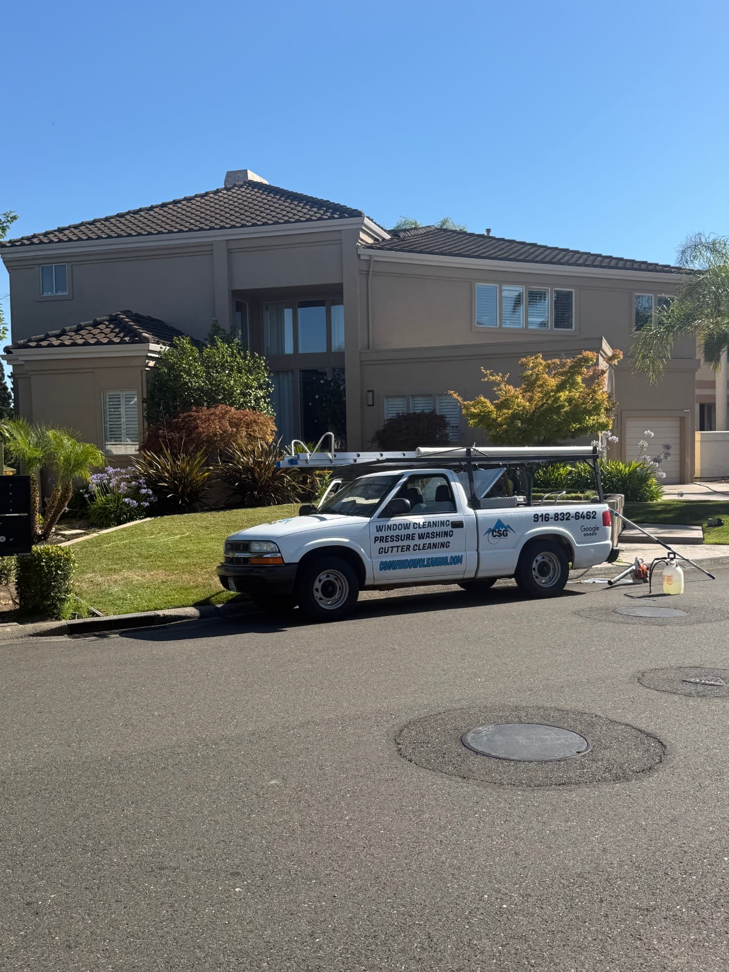 Two-story stucco home exterior soft-washed by CSG Window Cleaning with the CSG service truck parked out front