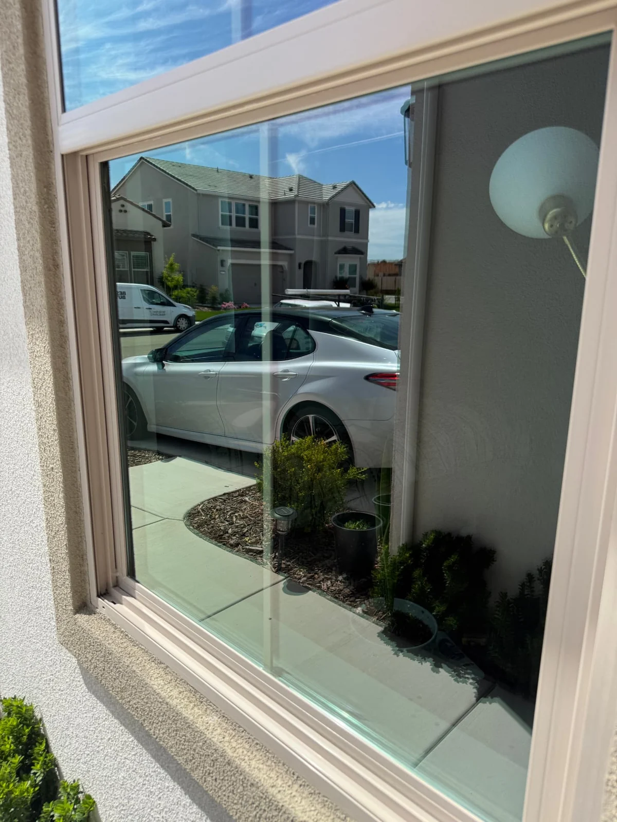 Close-up of a streak-free window pane reflecting a driveway and trees