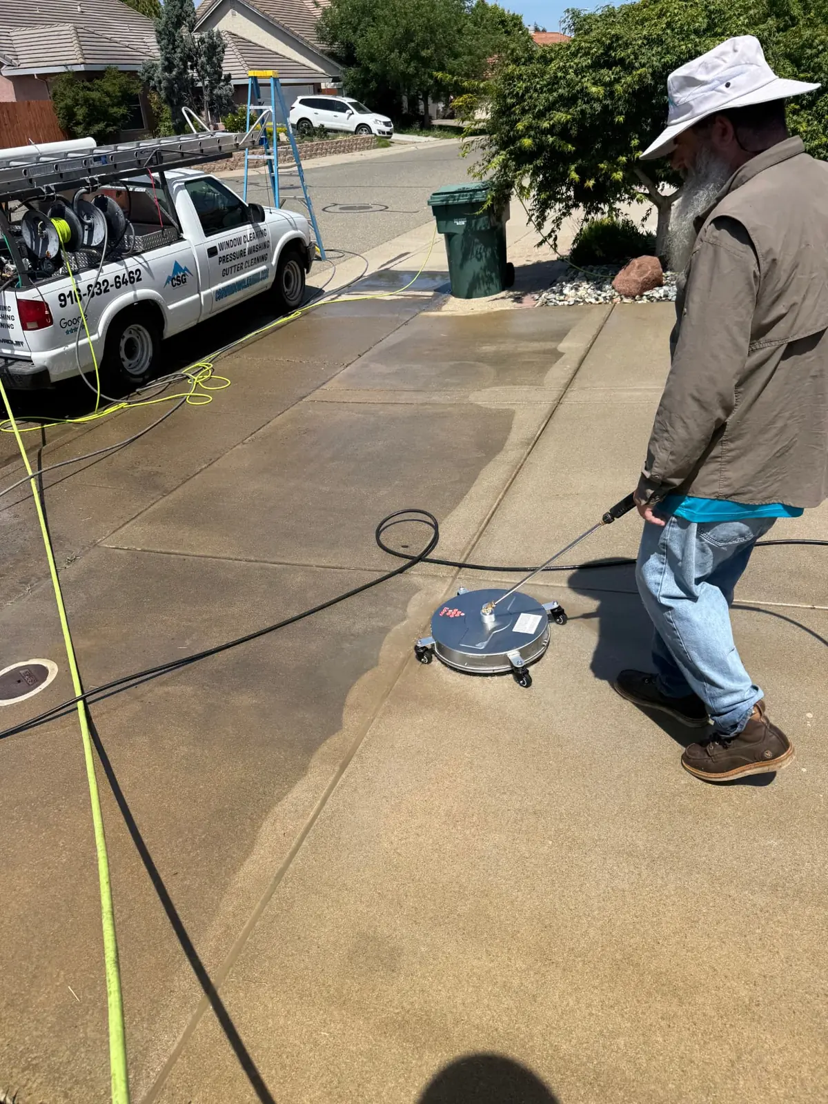 CSG technician surface-cleaning a concrete driveway with a rotary surface cleaner