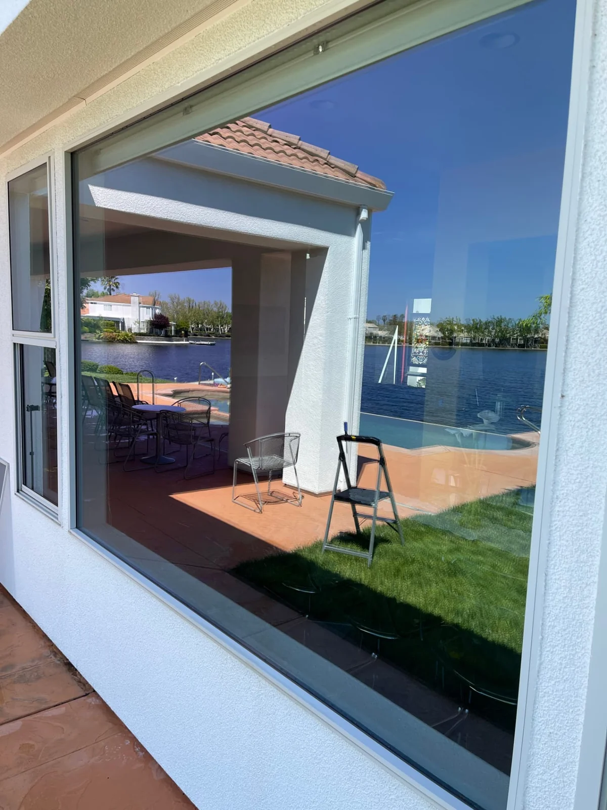 Large picture window cleaned inside and out, looking onto a covered patio and water