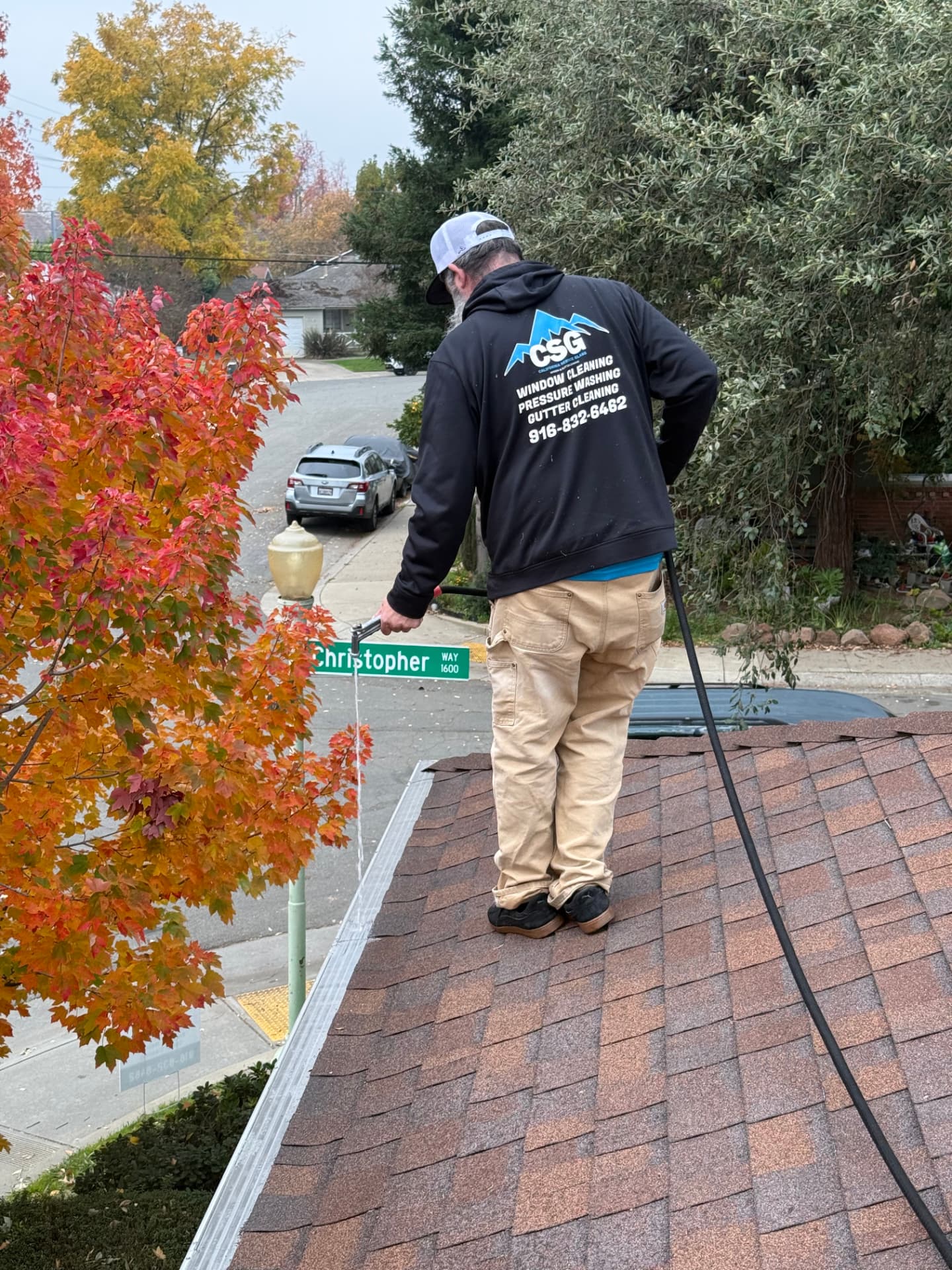 CSG technician clearing debris from rooftop gutters on a Sacramento home in autumn